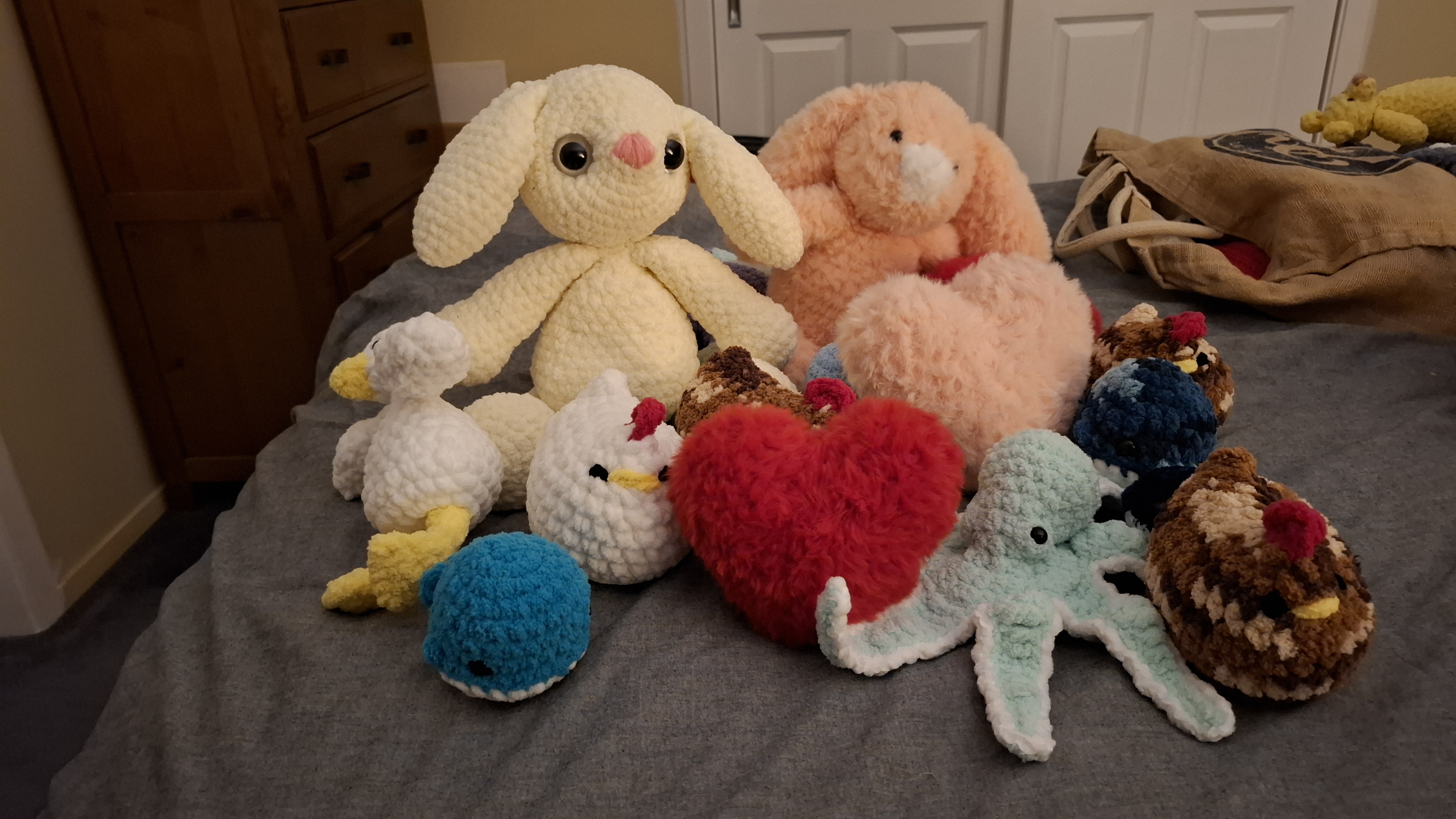 A collection of crocheted plush toys including bunnies, ducks, a whale, an octopus and hearts