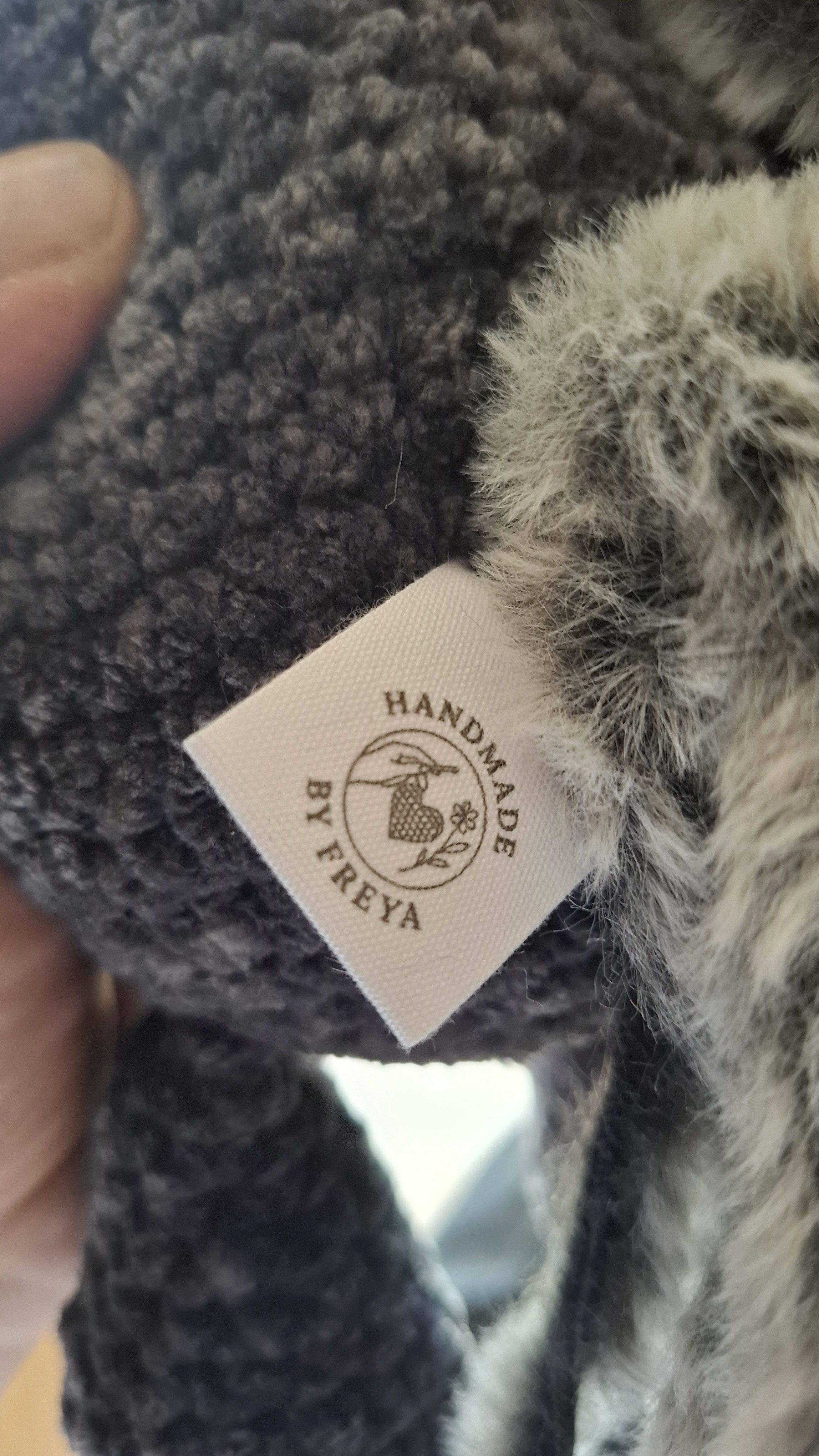 A woven Handmade by Freya label sewn into a grey chenille crochet piece