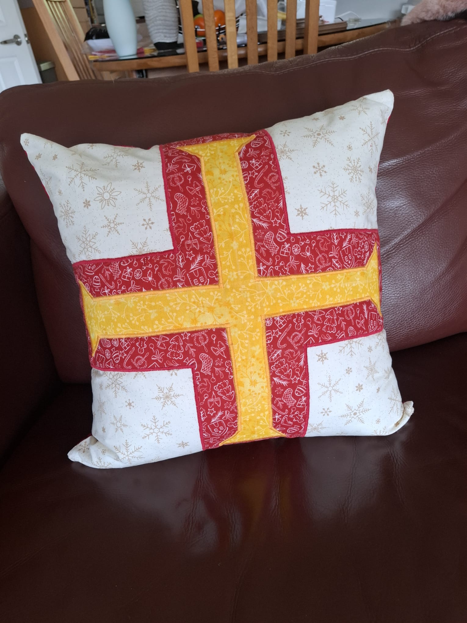 A cushion appliquéd with the Guernsey flag — a red cross with a gold Norman cross